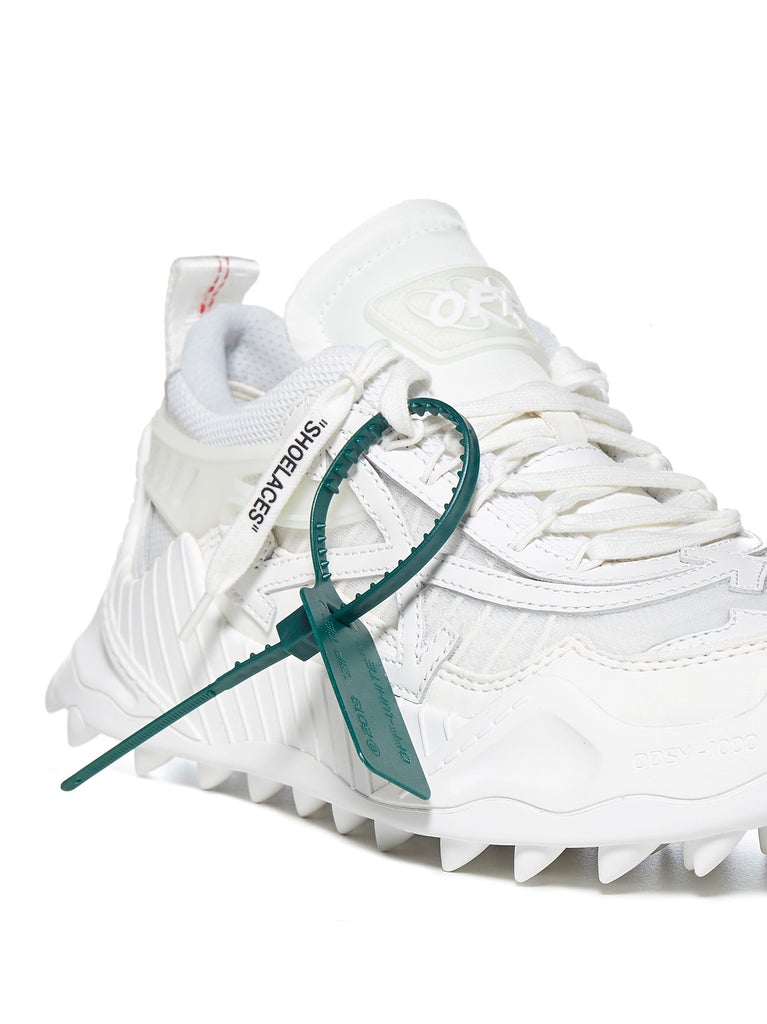 a white sneaker with a green hook on the side